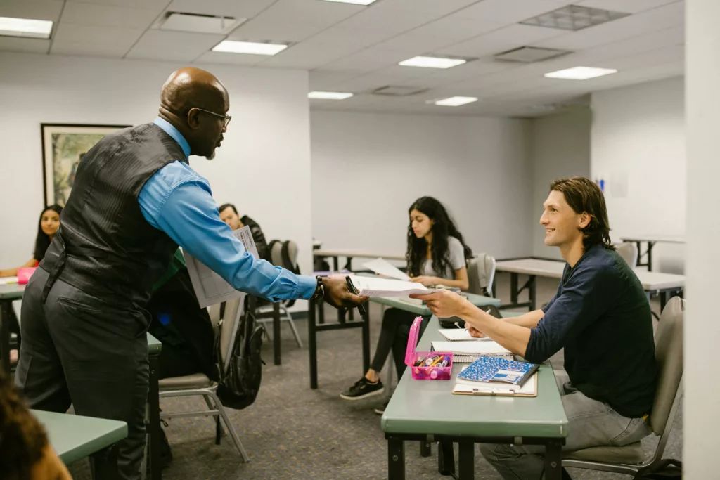 A teacher engaging with students in a university classroom, promoting active learning.